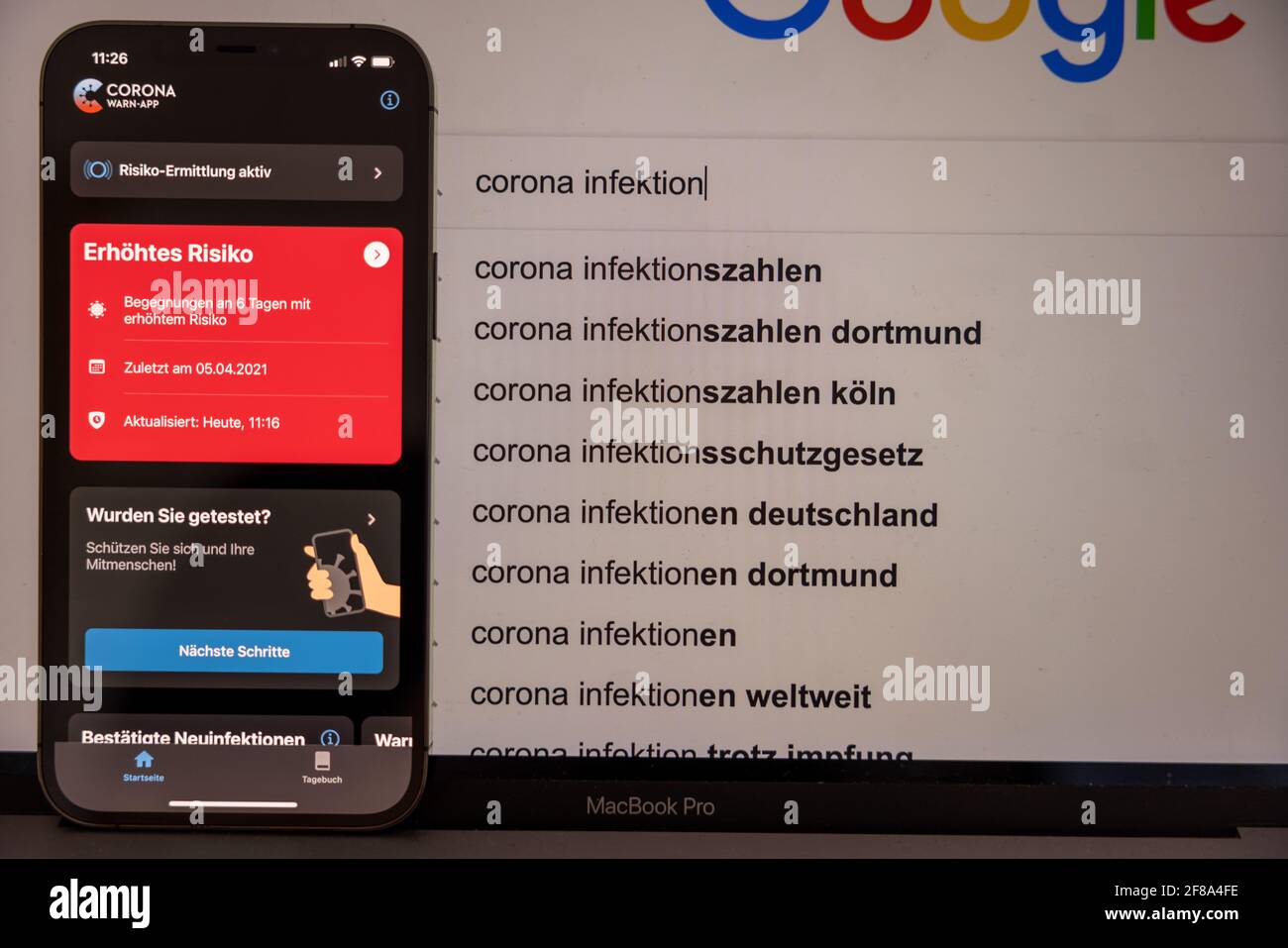 Düsseldorf, GERMANIA - Apr 12, 2021: Nahaufnahme von einem smartphone mit einer roten erhoehten Risiko Anzeige von der Corona warn App mit Deutschland Foto Stock