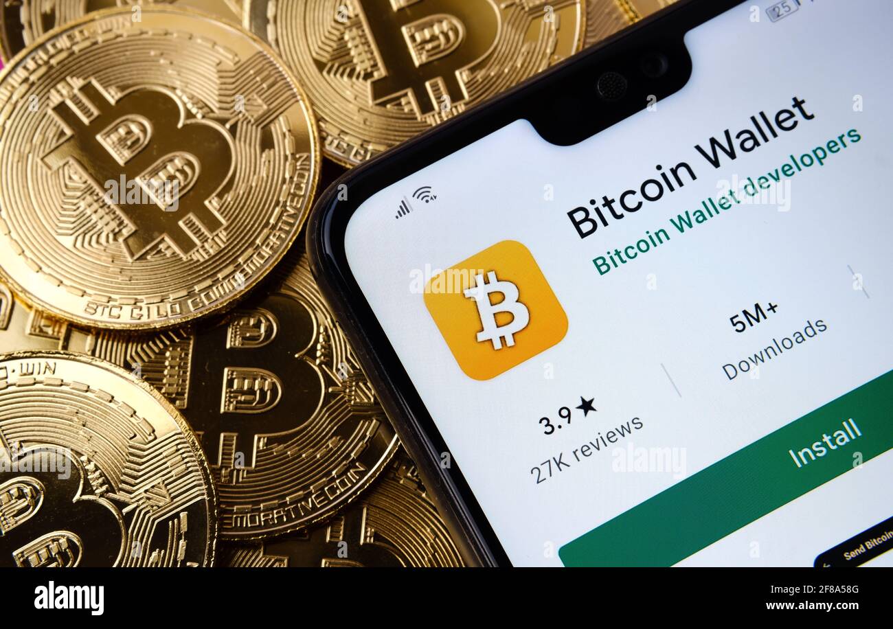 L'app Bitcoin Wallet visualizzata sullo schermo dello smartphone si trova sul mazzo di monete di bitcoin. Concetto. Stafford, Regno Unito, 12 aprile 2021. Foto Stock