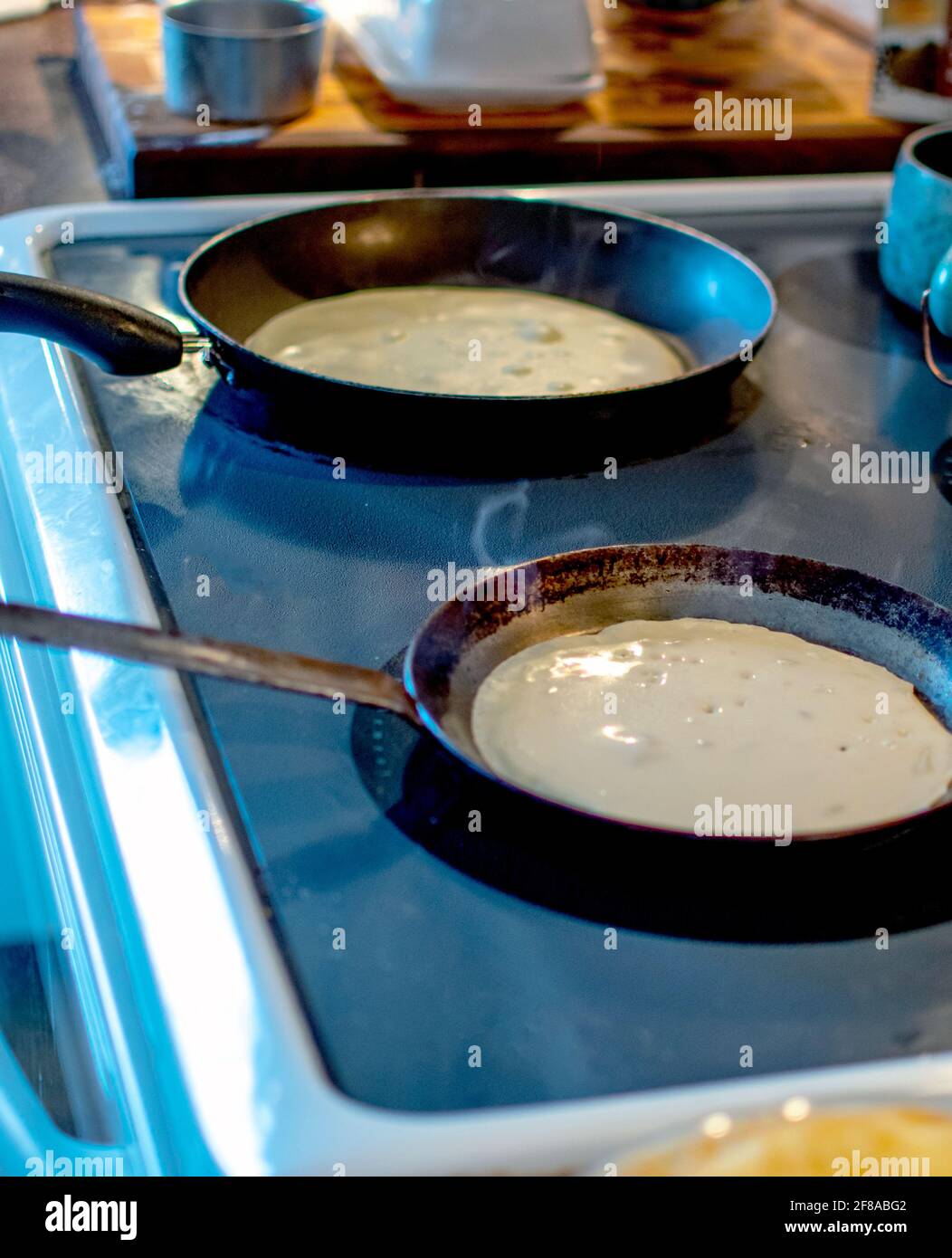 fare crepes con due padelle su un piano cottura Foto Stock