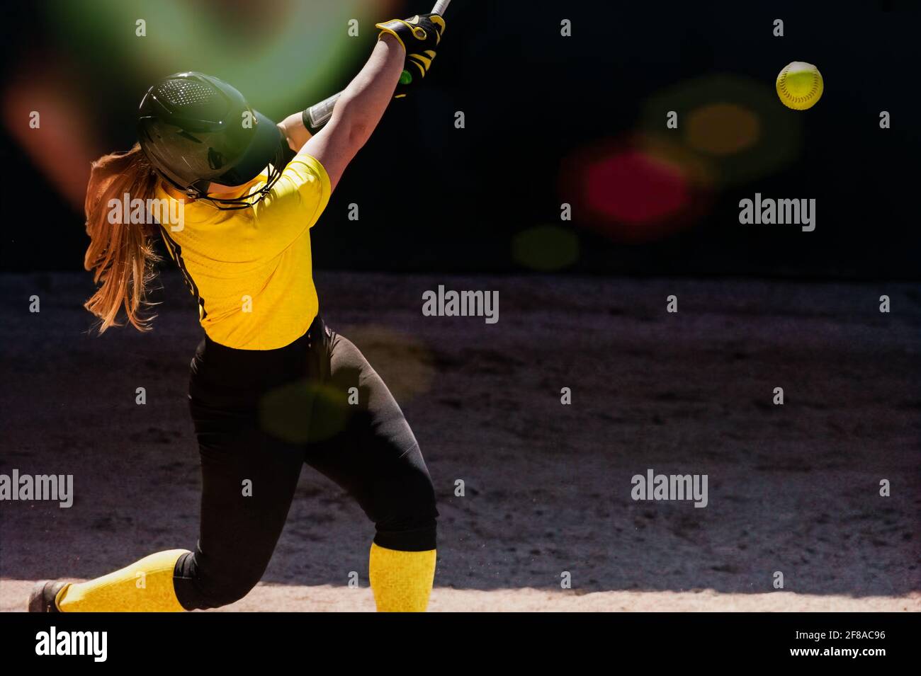 Un giocatore di baseball femminile sta oscillando per le recinzioni Foto Stock