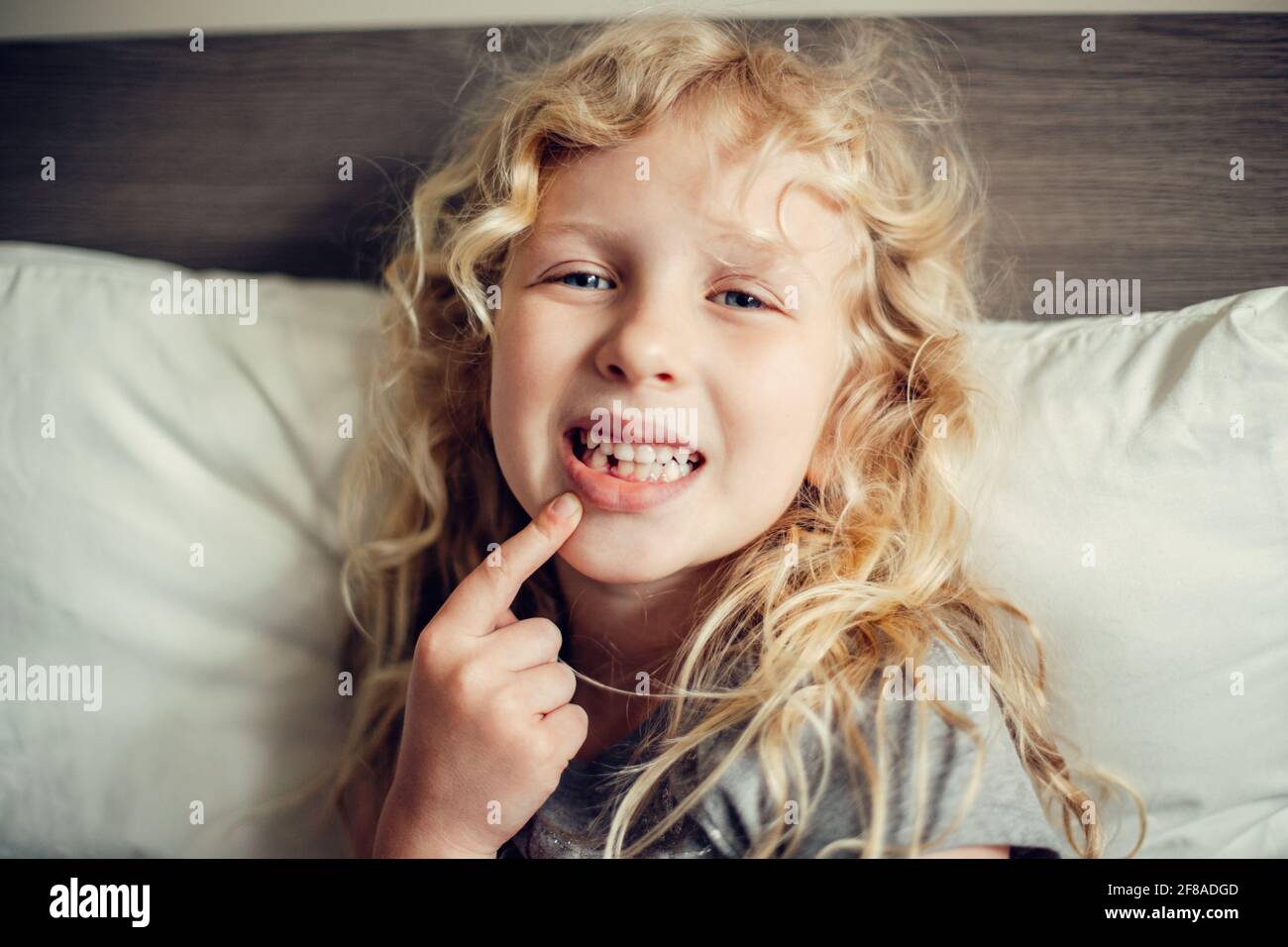 Cute caucasica bionda ragazza mostrando il suo dente mancante in bocca. Bambino orgoglioso che mostra il dente perso e si aspetta una fata dente che dà soldi. Crescere Foto Stock