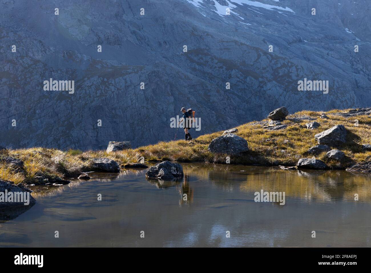 Escursionista passa un tarn alpino in Nuova Zelanda montagne Foto Stock