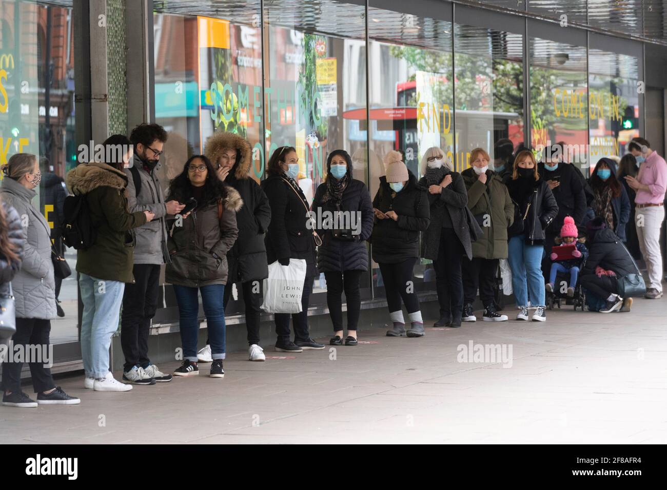 Londra, Regno Unito. 12 Aprile 2021. La foto scattata il 12 aprile 2021 mostra i clienti in coda per entrare in un grande magazzino a Londra, Gran Bretagna. In Inghilterra, tutti i negozi riaprono dal lunedì insieme ai parrucchieri, ai saloni di bellezza e ad altri servizi a contatto diretto. I ristoranti e i pub sono autorizzati a servire cibo e alcol ai clienti seduti all'aperto. Nel frattempo, palestre, terme, giardini zoologici, parchi a tema, le biblioteche e i centri comunitari possono aprirsi. Credit: Ray Tang/Xinhua/Alamy Live News Foto Stock