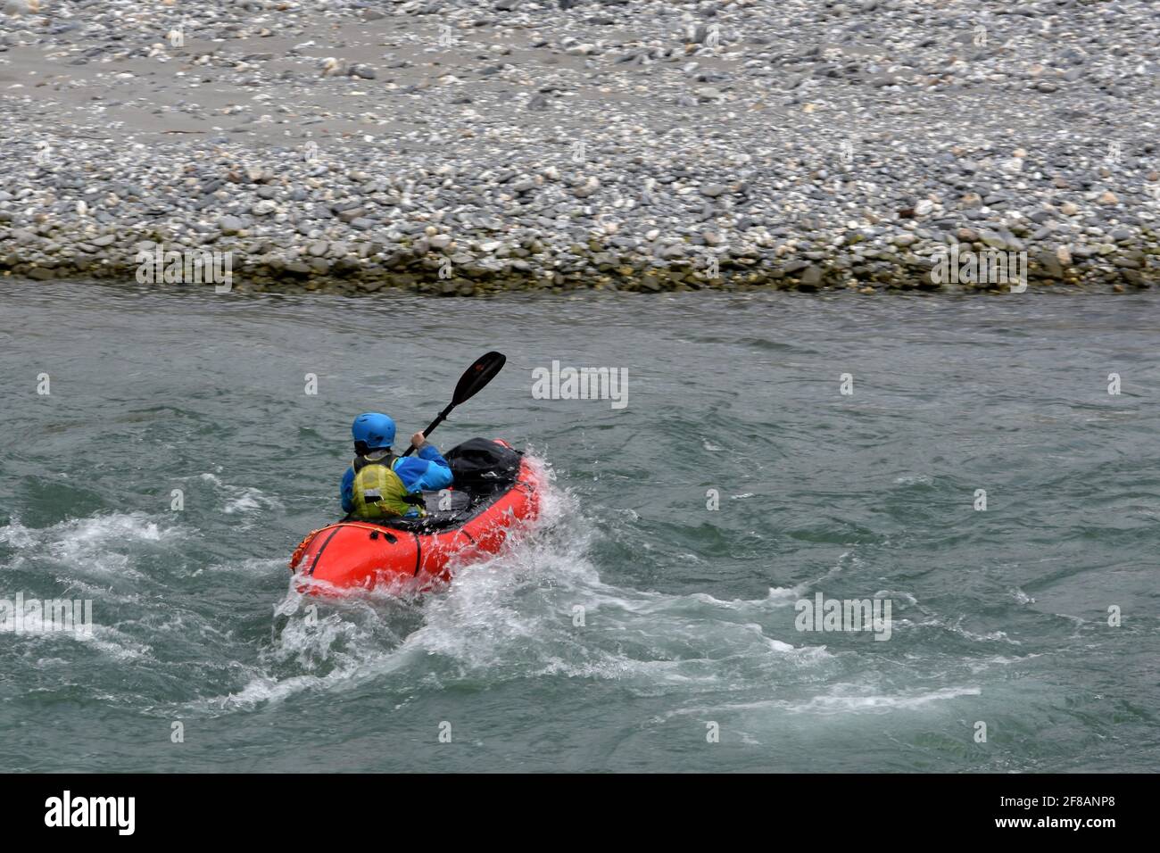 Kayak sulle acque bianche nella gola del Reno Ruinaulta in Svizzera. È in vista posteriore manovrando con remi per mantenere il corso ed evitare la riva del fiume. Foto Stock