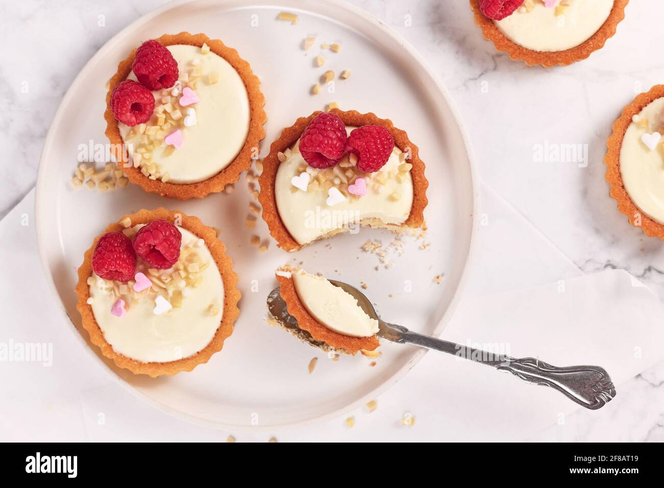 Piccola pasticceria a base di tartine con panna bianca, ricoperta di lamponi e mandorle Foto Stock