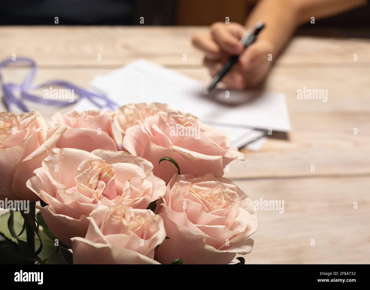 Sposa ragazza firma inviti a nozze, in primo piano delicato rosa bouquet di rosa da sposo Foto Stock