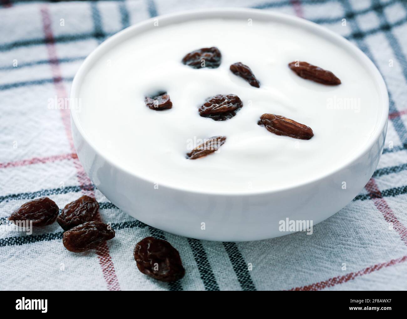 Yogurt fresco con uvetta secca in un recipiente Foto Stock