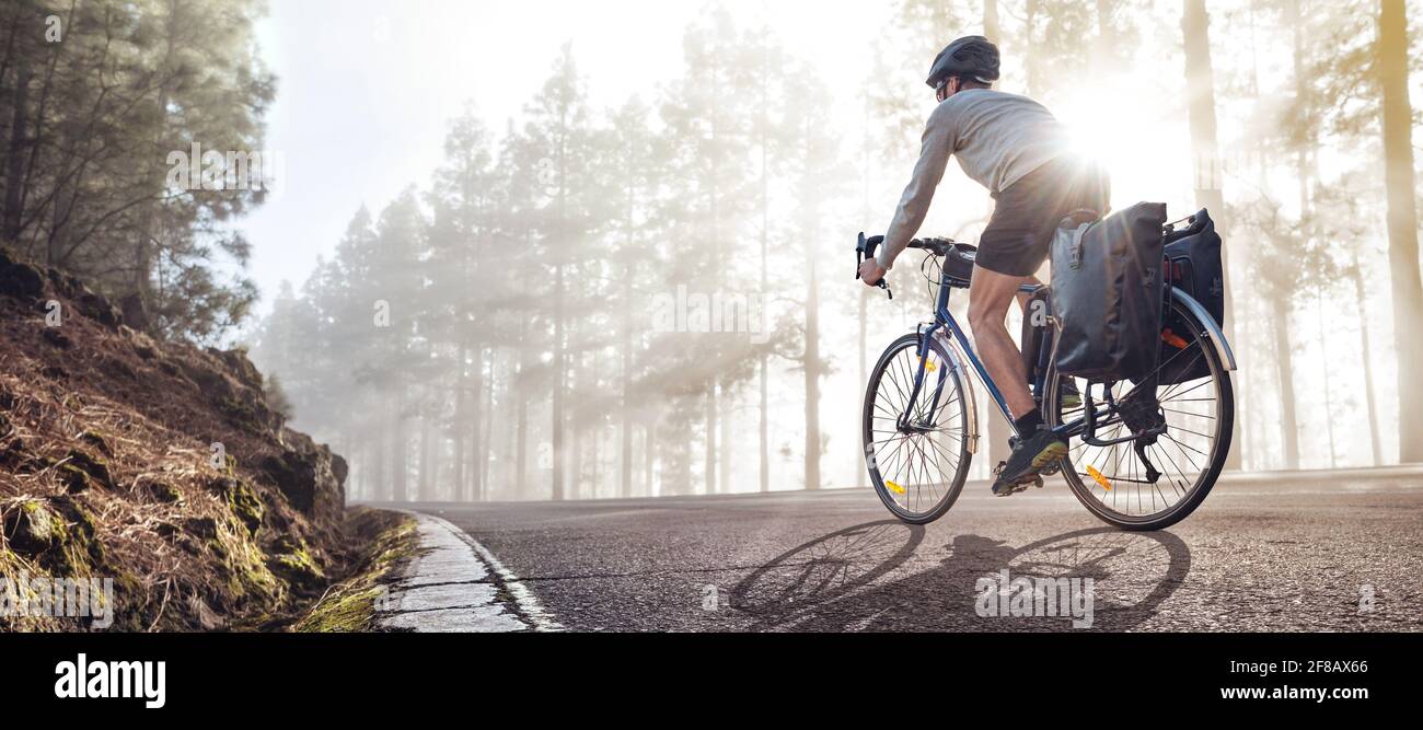 Ciclista in bicicletta con panniere che cavalcano lungo una nebbia strada forestale Foto Stock