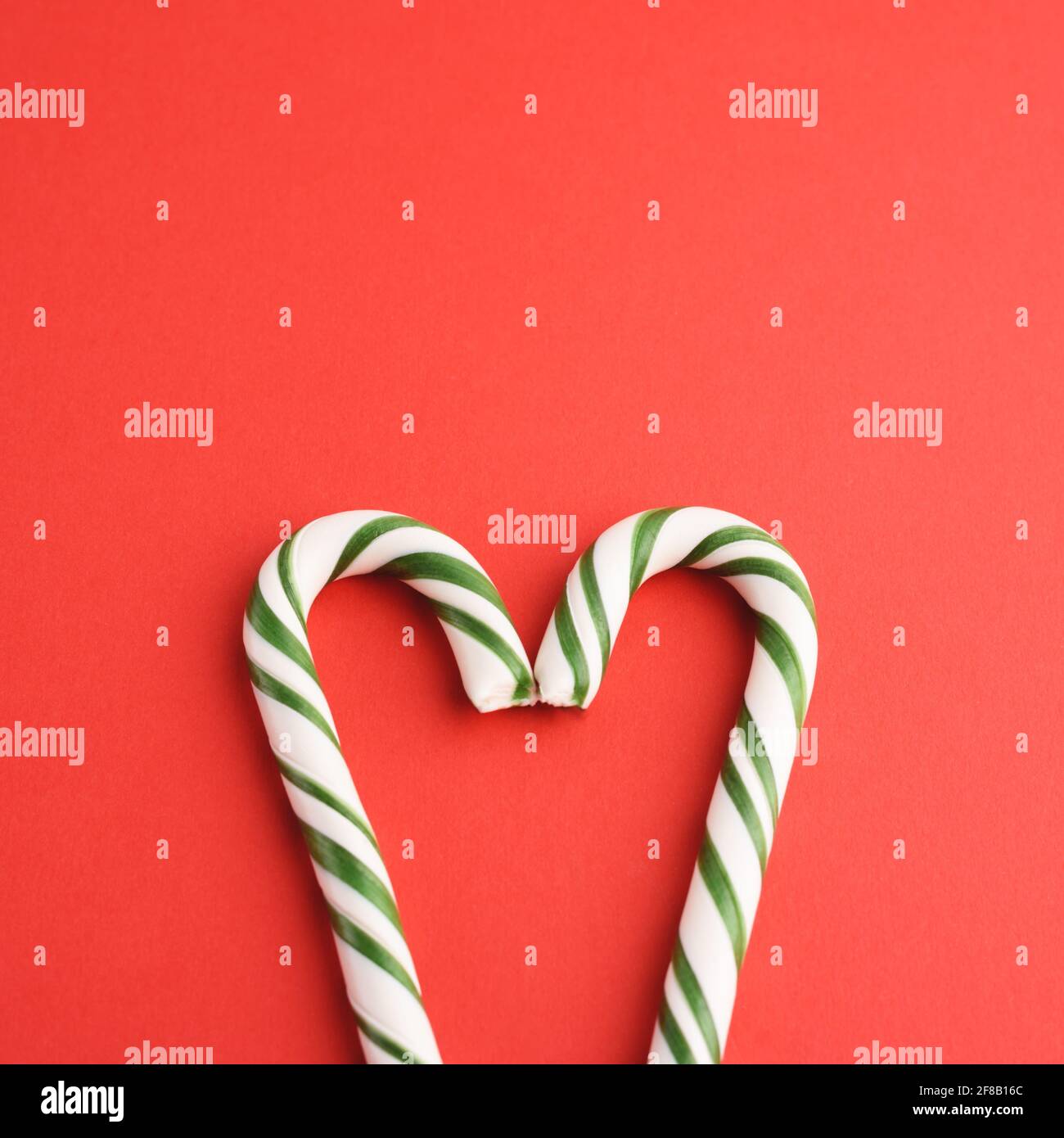 Caramelle dure a forma di cuore bianco e verde a strisce natalizie sul dorso rosso. Foto Stock