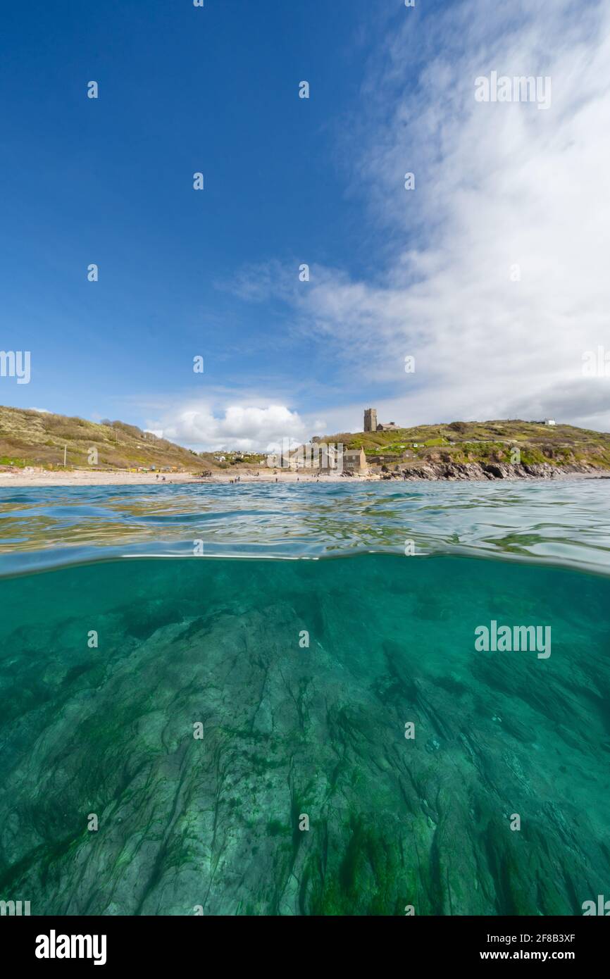 Wembury Beach a metà e metà mostra la chiesa di Wembury e il fondale roccioso. Foto Stock