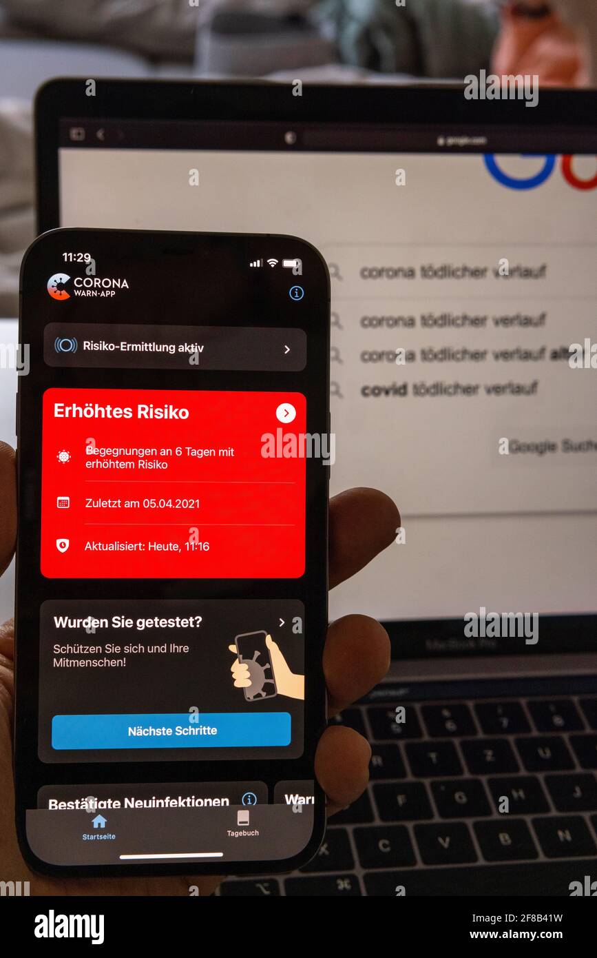 Düsseldorf, GERMANIA - Apr 12, 2021: Nahaufnahme von einem smartphone mit einer roten erhoehten Risiko Anzeige von der Corona warn App mit Deutschland Foto Stock