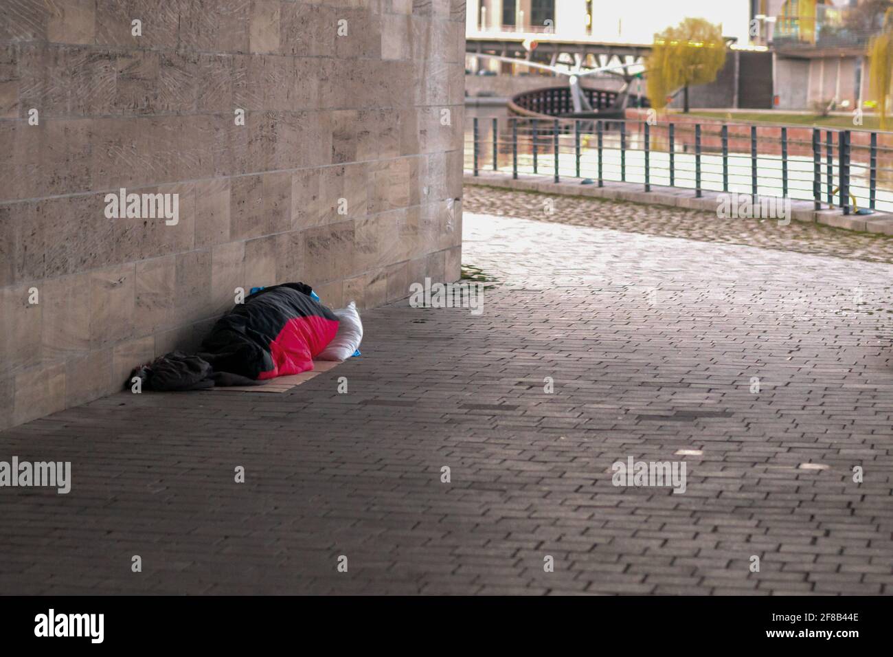 Un uomo senza casa in un sacco a pelo sotto un ponte Foto Stock
