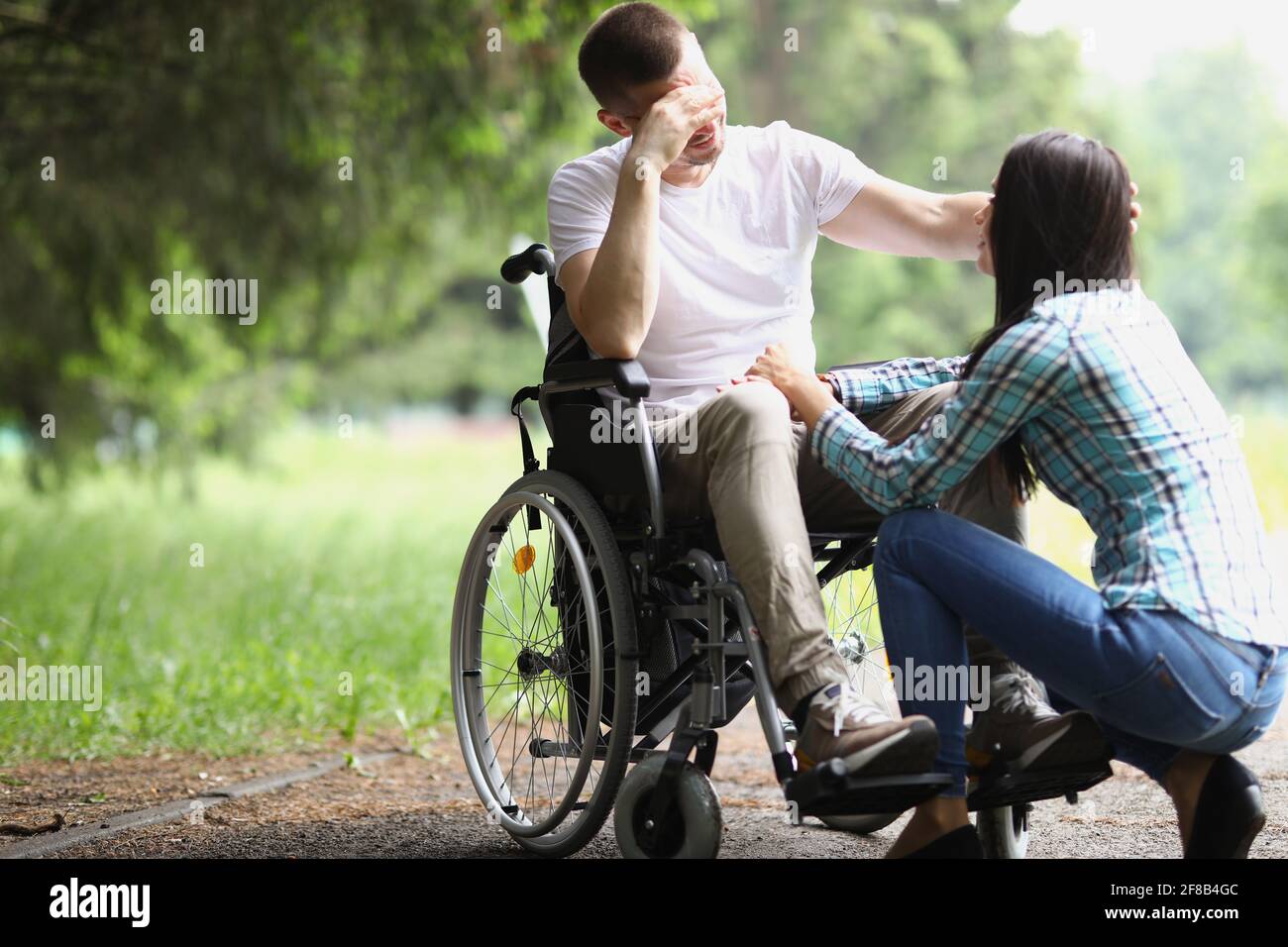 L'uomo disabile in sedia a rotelle comunica con la donna nel parco Foto Stock