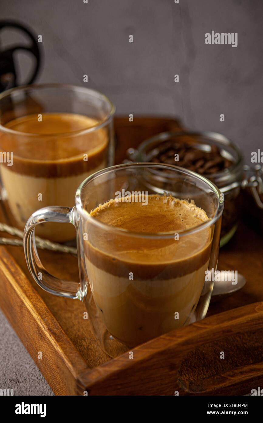 Dalgona Coffee - la bevanda coreana di caffè su sfondo di legno. Caffè istantaneo o espresso in polvere con zucchero e acqua calda. Algone montato ghiacciato Foto Stock