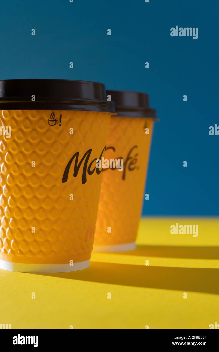 Ucraina, Kiev - 17 febbraio 2021: Bicchiere giallo di caffè da McDonald's. Bicchiere di carta bere McCafe. Tazza offee sul tavolo con ombre. Menu nel ristorante fast food. Foto Stock