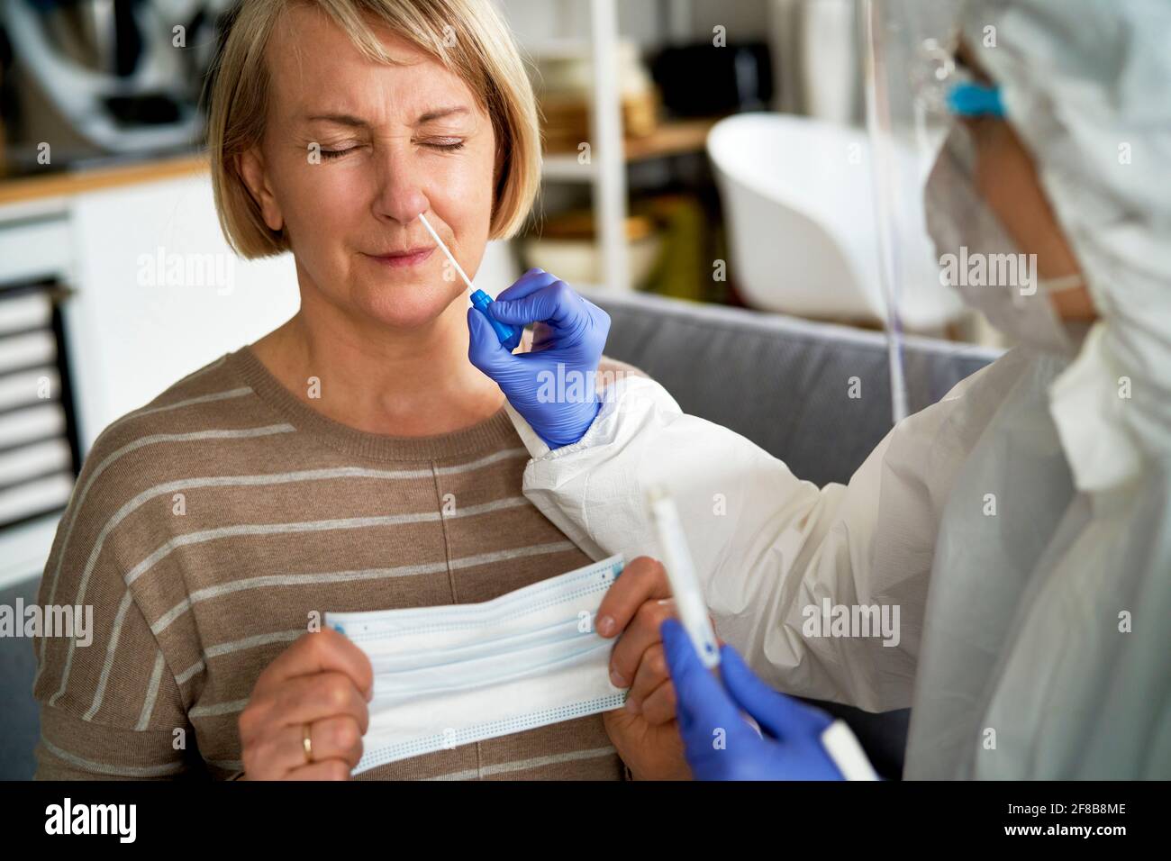 Medico femminile che prende un test con tampone nasale da un anziano donna Foto Stock