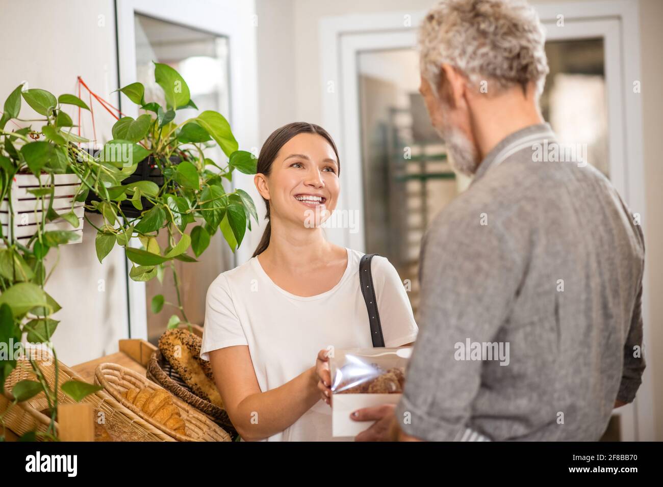 Donna felice che prende scatola dei panini dal venditore Foto Stock Donna felice che prende scatola dei panini dal venditore Foto Stock