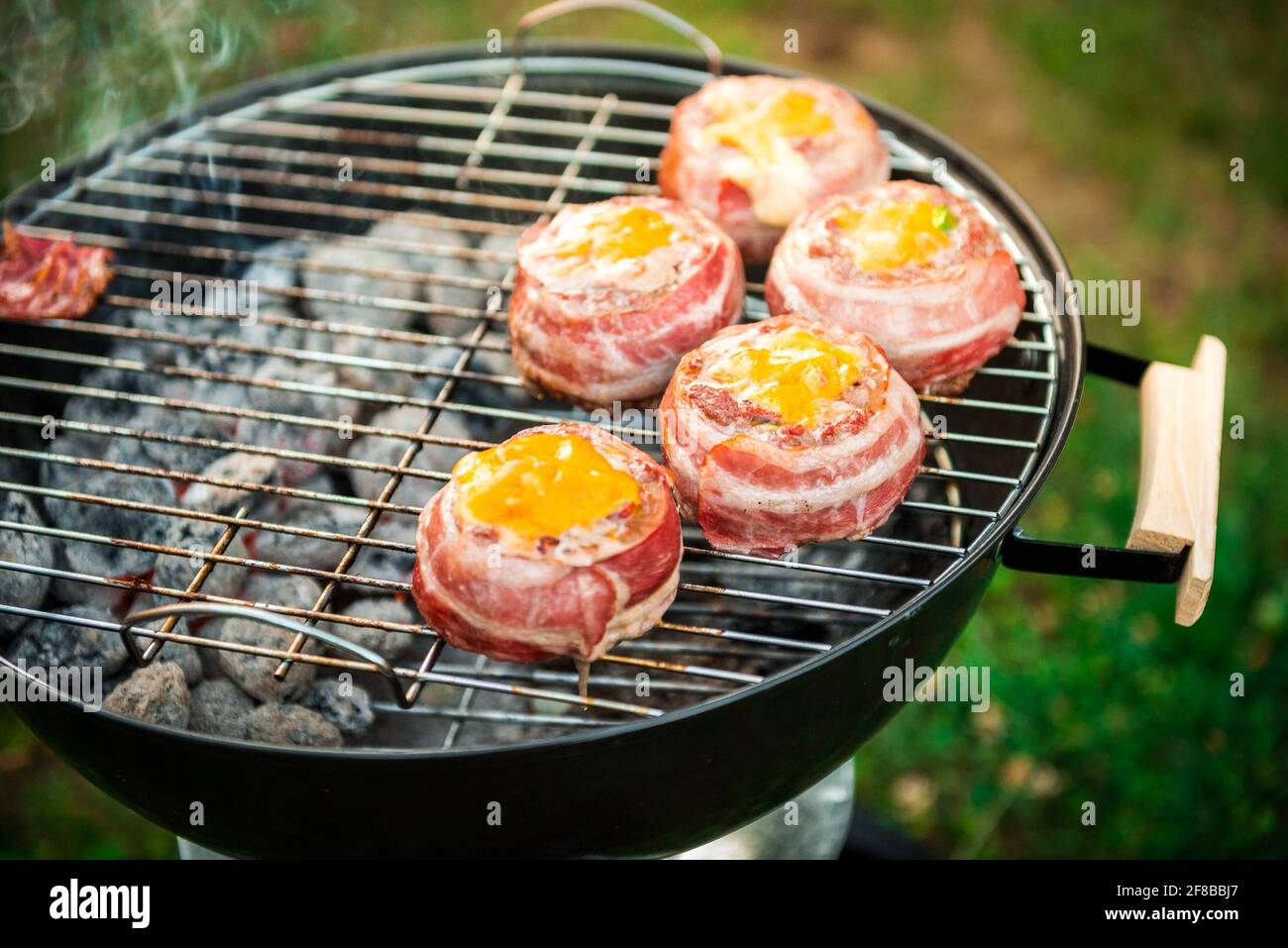 Rendendo fatta in casa birra può Bacon gli hamburger sul grill barbecue. La preparazione di polpette ripiene, avvolto in pancetta e grigliare sul calore indiretta nella natura a bac Foto Stock
