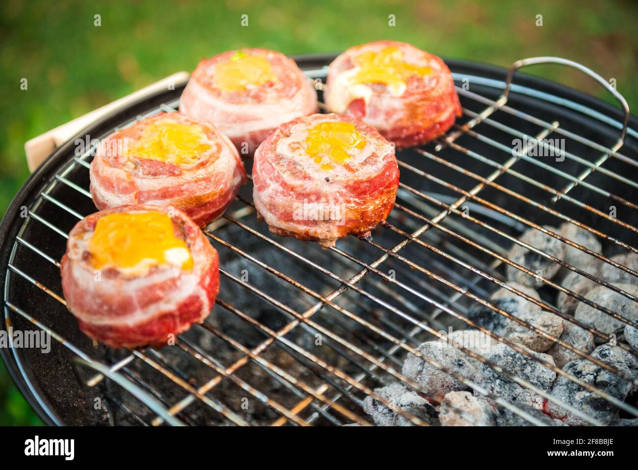 Rendendo fatta in casa birra può Bacon gli hamburger sul grill barbecue. La preparazione di polpette ripiene, avvolto in pancetta e grigliare sul calore indiretta nella natura a bac Foto Stock