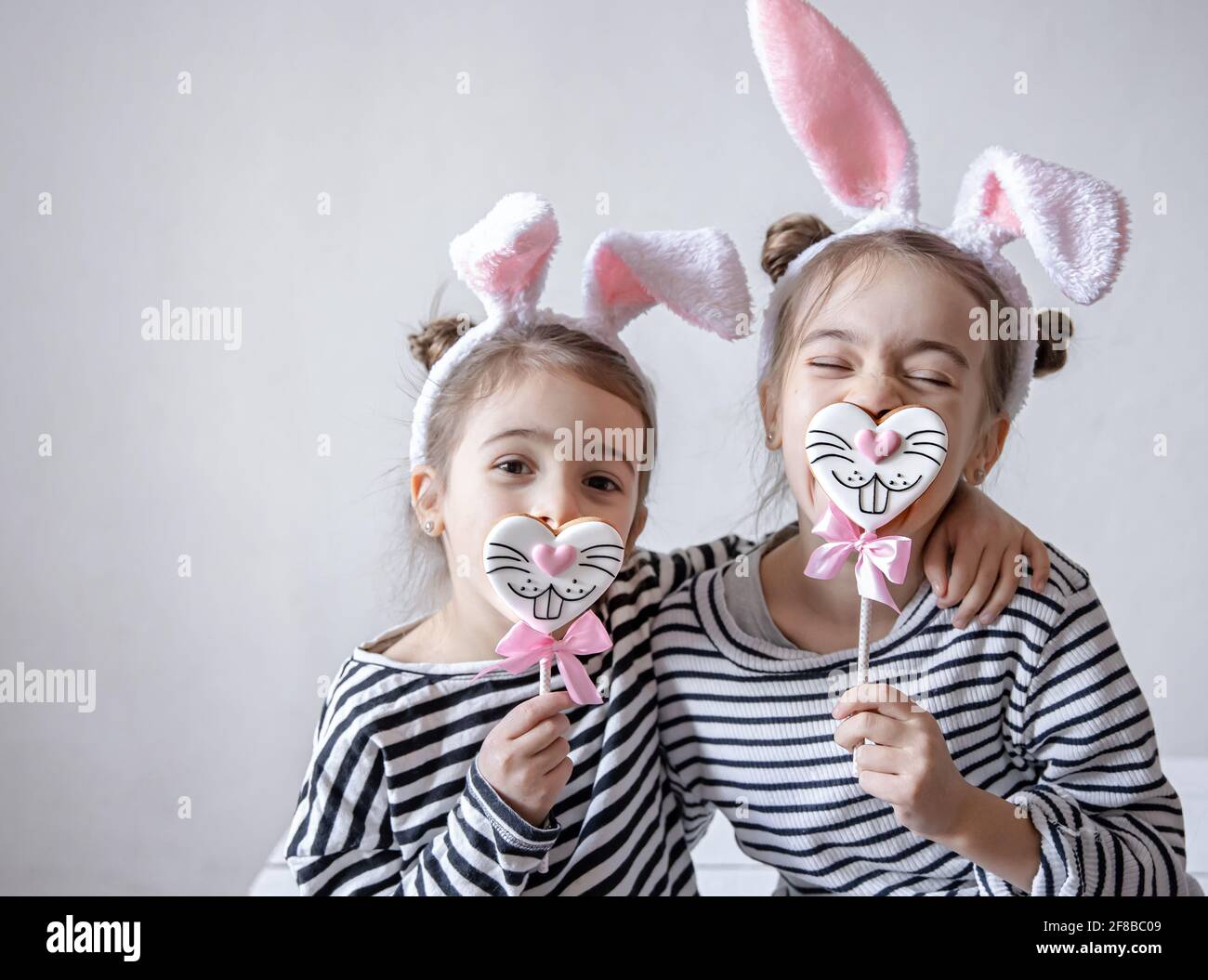 Bambine divertenti con orecchie pasquali sulla testa e pan di zenzero  pasquale su bastoni Foto stock - Alamy