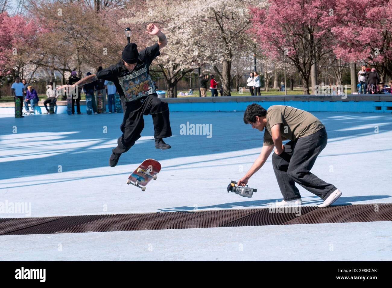 Un gruppo di skateboarder viene girato facendo acrobazie. Vicino all'Unisphere a Flushing Meadows Corona Park, a Queens, New York. Foto Stock