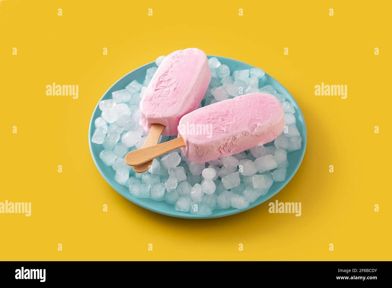 Popsicle di fragole e ghiaccio tritato su piatto blu su giallo sfondo Foto Stock