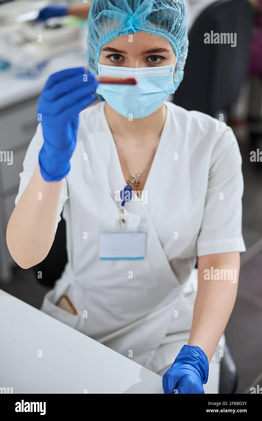 Tecnico di laboratorio esperto che esamina il contenuto della provetta Foto Stock