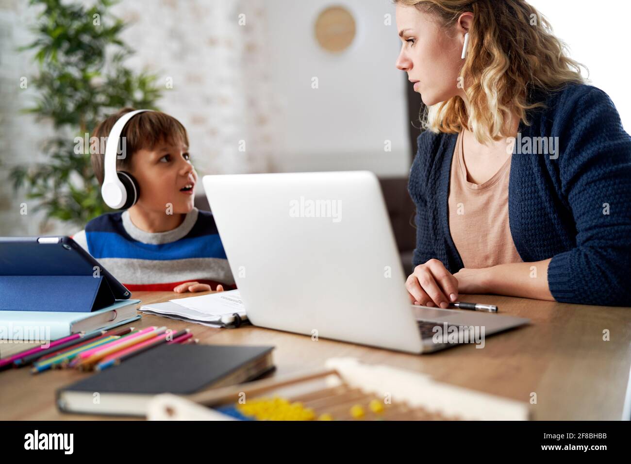 Il figlio disturba la mamma nell'ufficio domestico Foto Stock