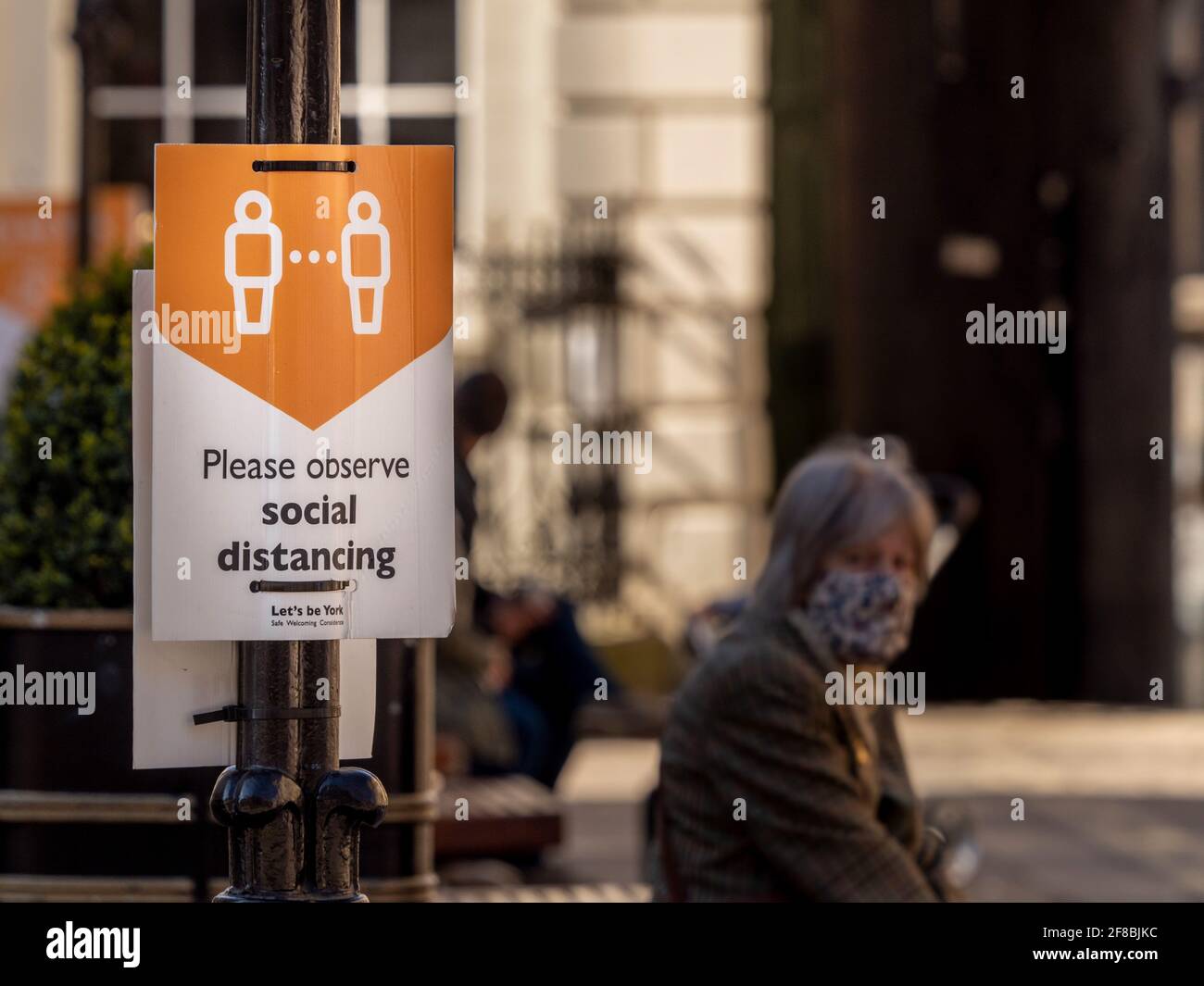 Caucasico caucasico indossare un volto di copertura seduta da un segno sociale di distanza a York, dopo aver alleggerito le restrizioni di blocco covid-19. Foto Stock