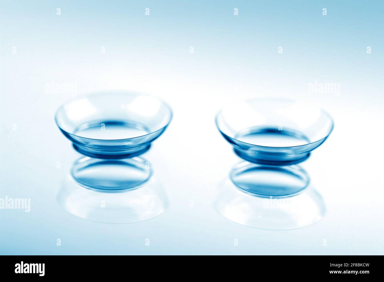 Due lenti a contatto con riflessi su superfici blu. Foto Stock