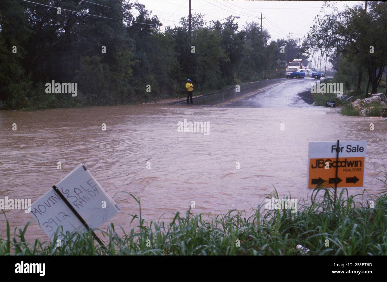La polizia blocca la strada dove Williamson Creek inonda un attraversamento di acque basse durante un'inondazione in un'area residenziale di Austin, Texas. ©Bob Daemmrich Foto Stock