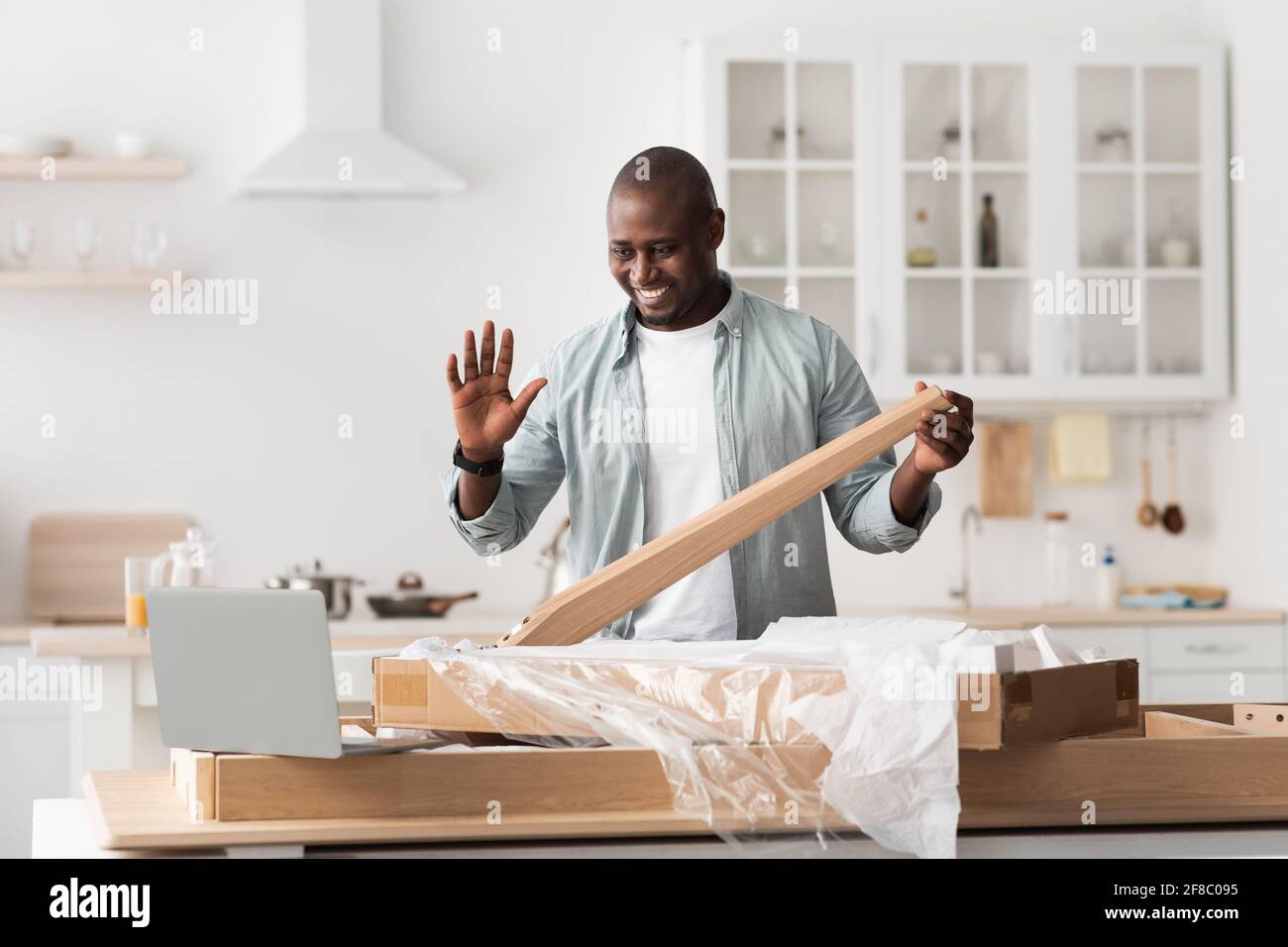 Manuale nero istruzioni video per assemblare i mobili a casa con le mani, muovendosi verso il computer portatile a casa Foto Stock