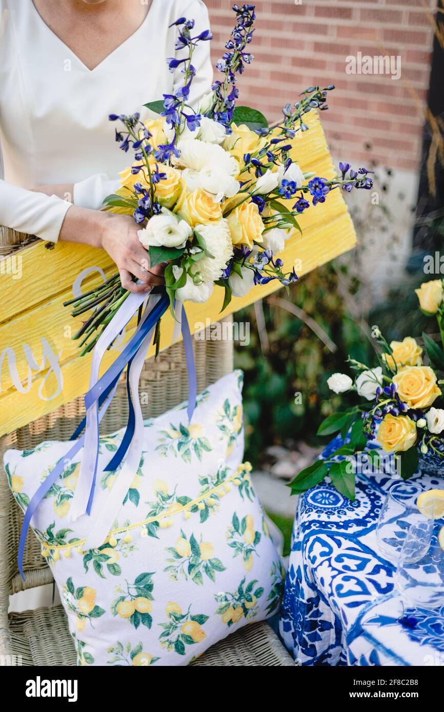 La sposa tiene il bel bouquet vibrante di nozze di giallo e bianco rose con accenti blu scuro Foto Stock