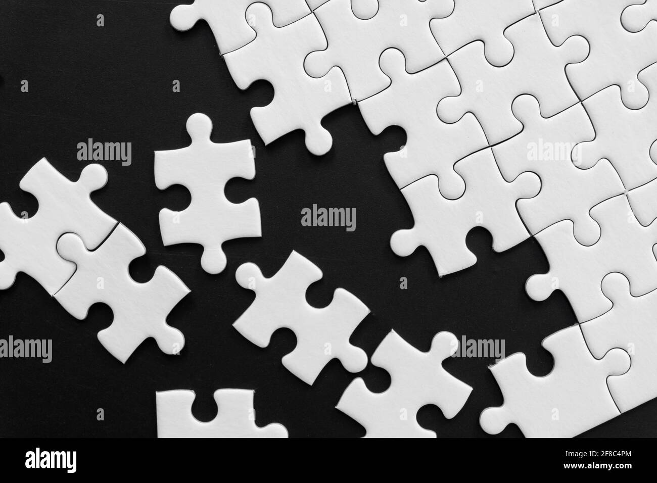 Pezzi di puzzle bianco incompiuto su sfondo nero Foto Stock