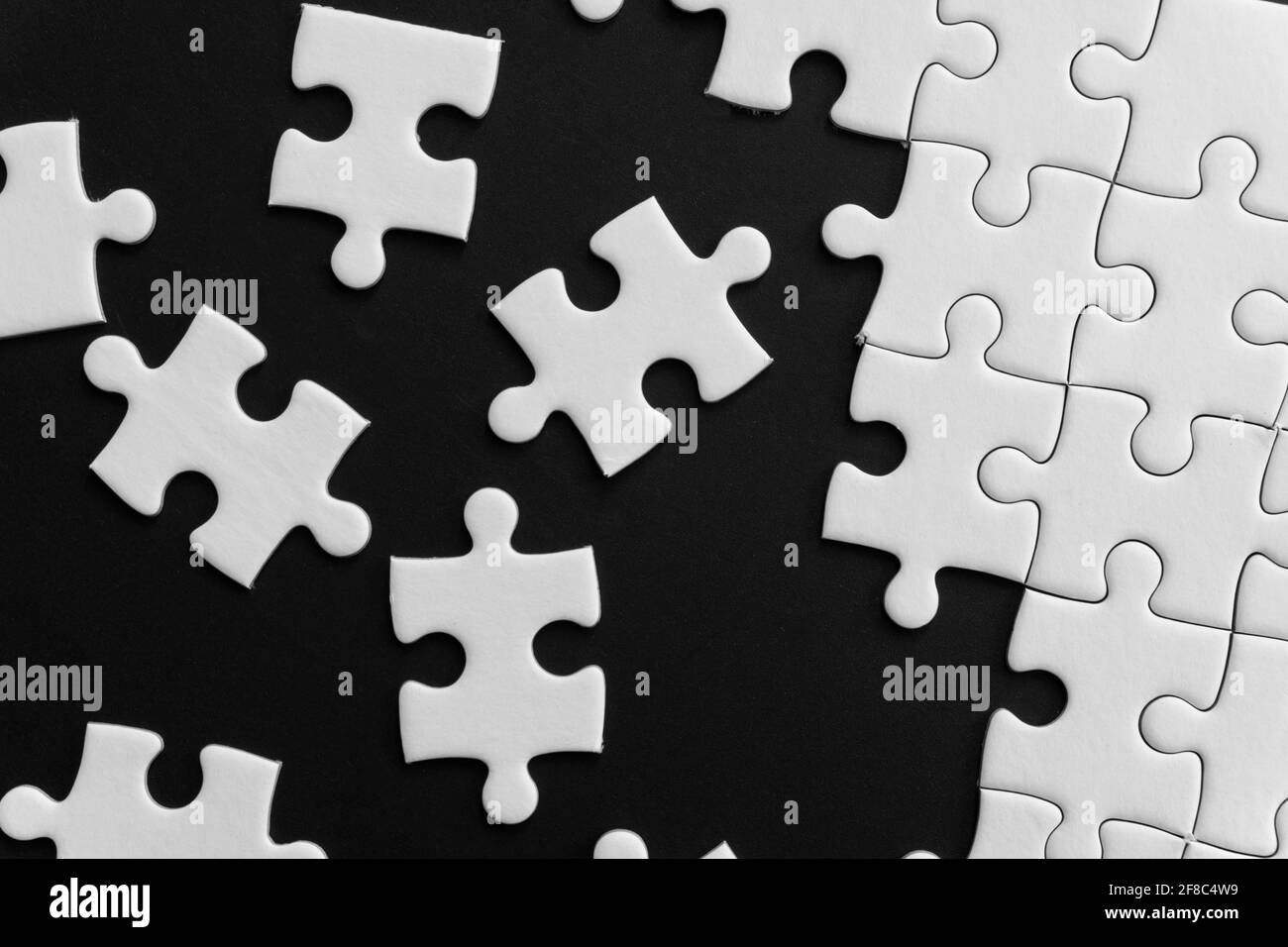 Pezzi di puzzle bianco incompiuto su sfondo nero Foto Stock