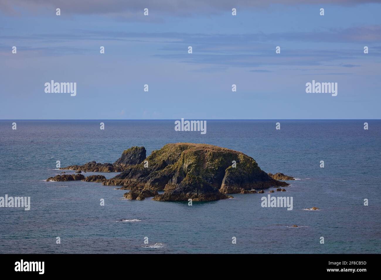 primo piano le formazioni rocciose a forma di isola circondate dall'acqua atlantica. Kilfarrasy Beach. Co.Waterford Coastline, Irlanda Foto Stock