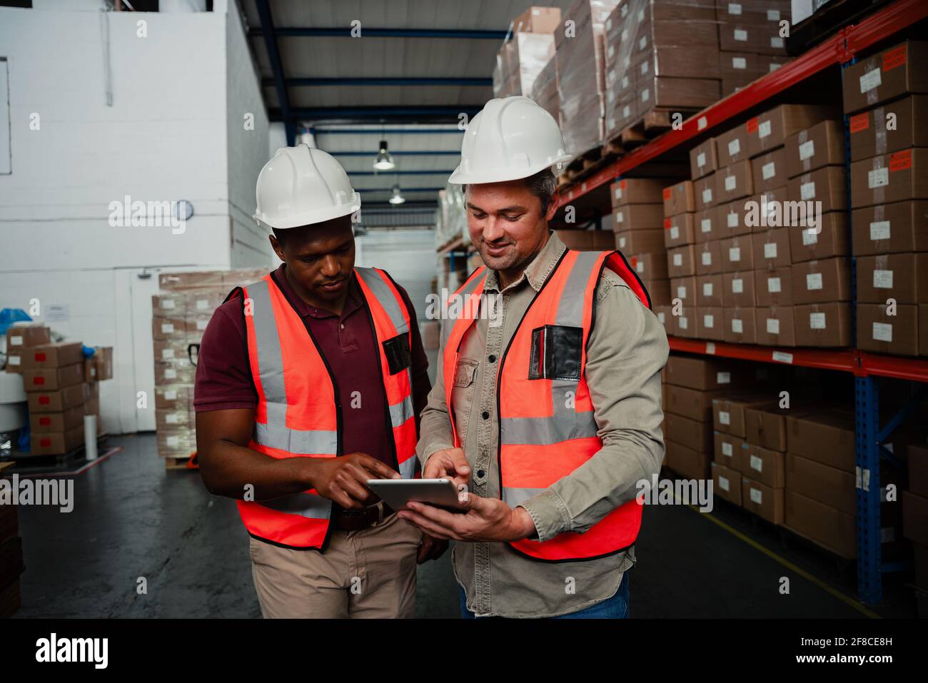 Due colleghi che lavorano in fabbrica sorridendo alle immagini digitali tablet Foto Stock