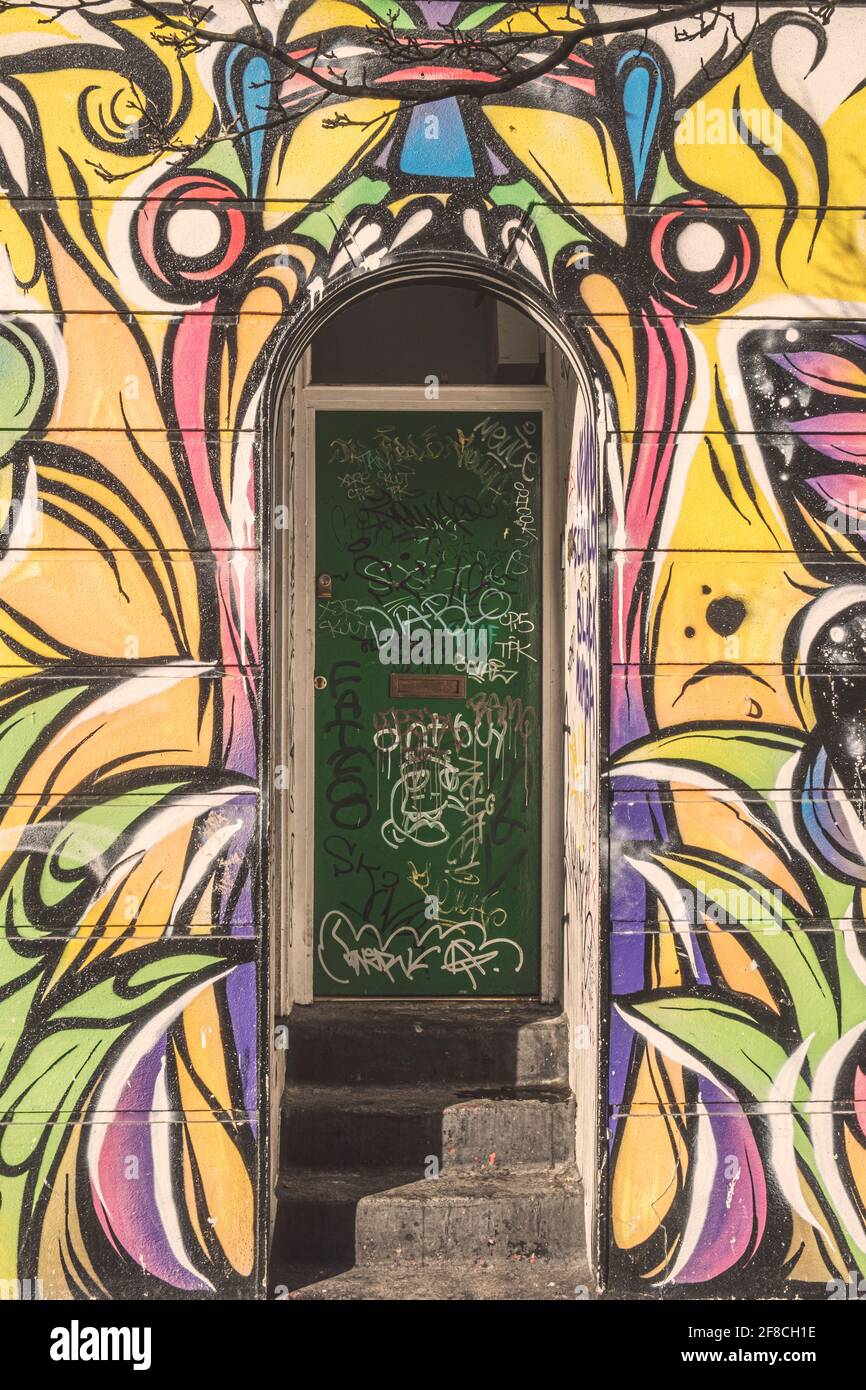 Ingresso a una casa di squat a Londra, coperta di graffiti e con arte di strada di una bocca gaping, Camden Town, Londra, Regno Unito Foto Stock