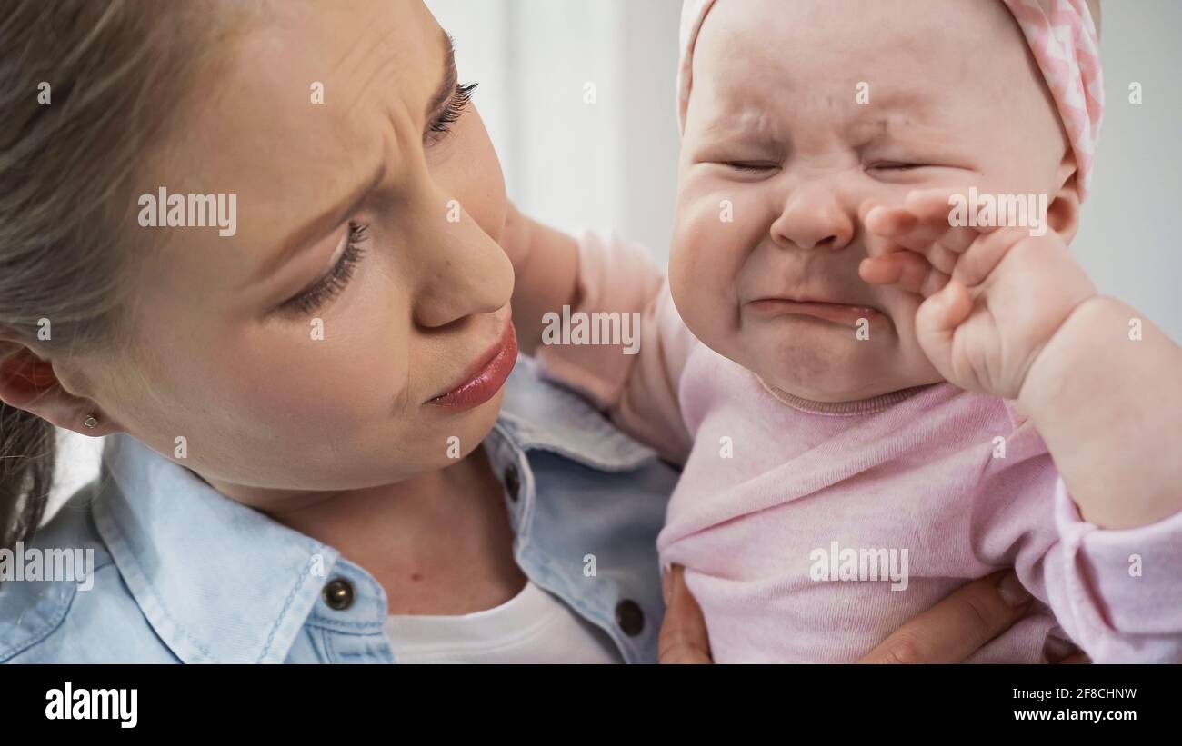 madre che tiene il bambino piangente triste nelle braccia Foto Stock