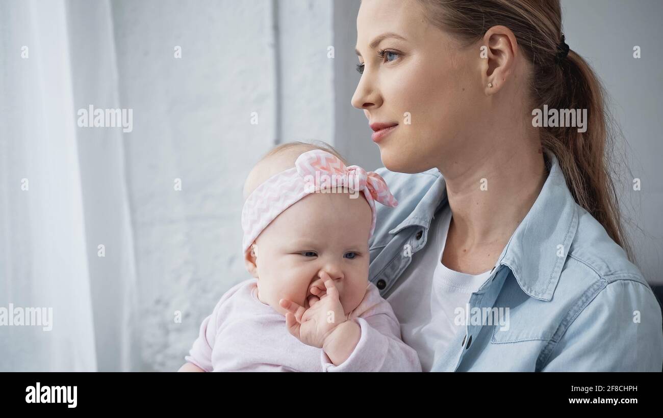 madre che tiene in armi figlia del bambino e che guarda via Foto Stock