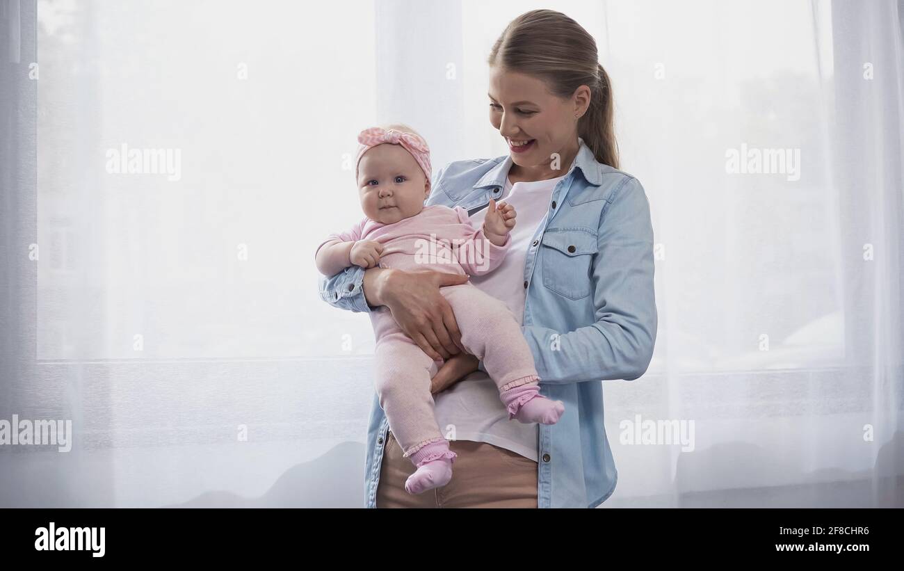 gioiosa madre che tiene in armi figlia del bambino Foto Stock