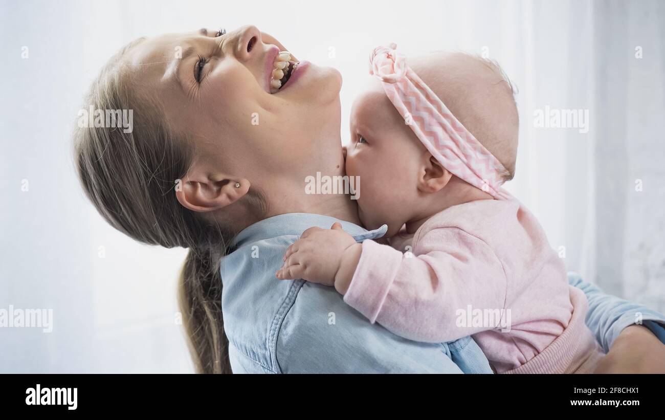 madre felice che tiene in armi bambina e ridendo a. casa Foto Stock