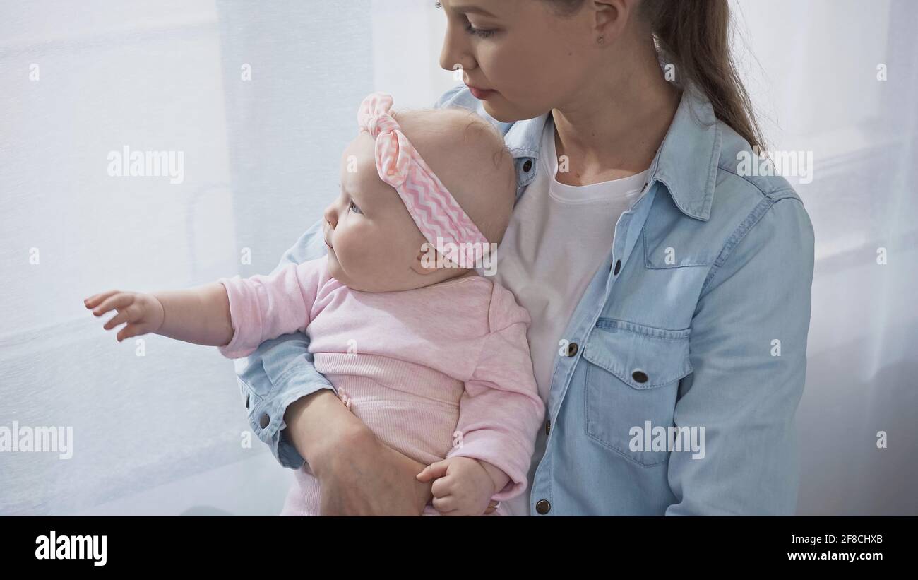 madre che tiene in armi bambina a casa Foto Stock
