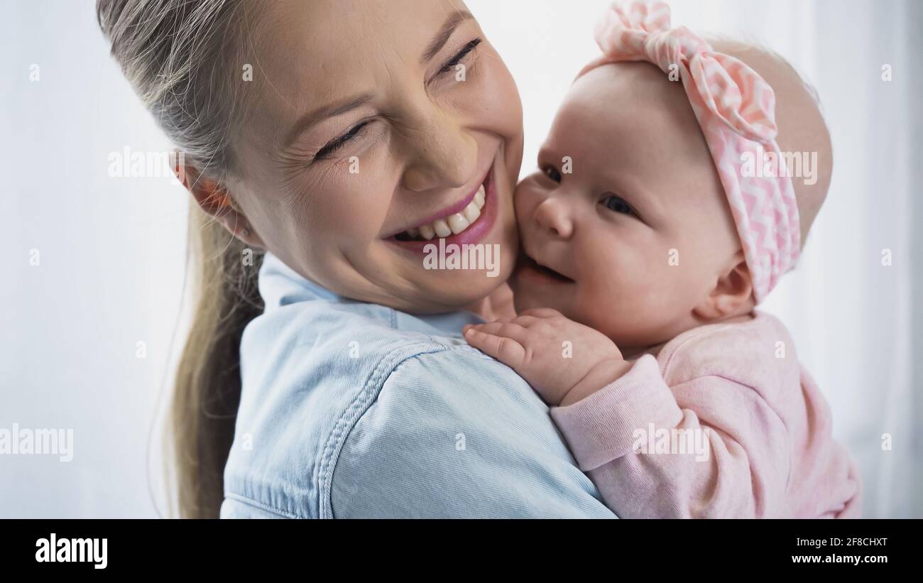 madre allegra che tiene in armi felice figlia del bambino Foto Stock