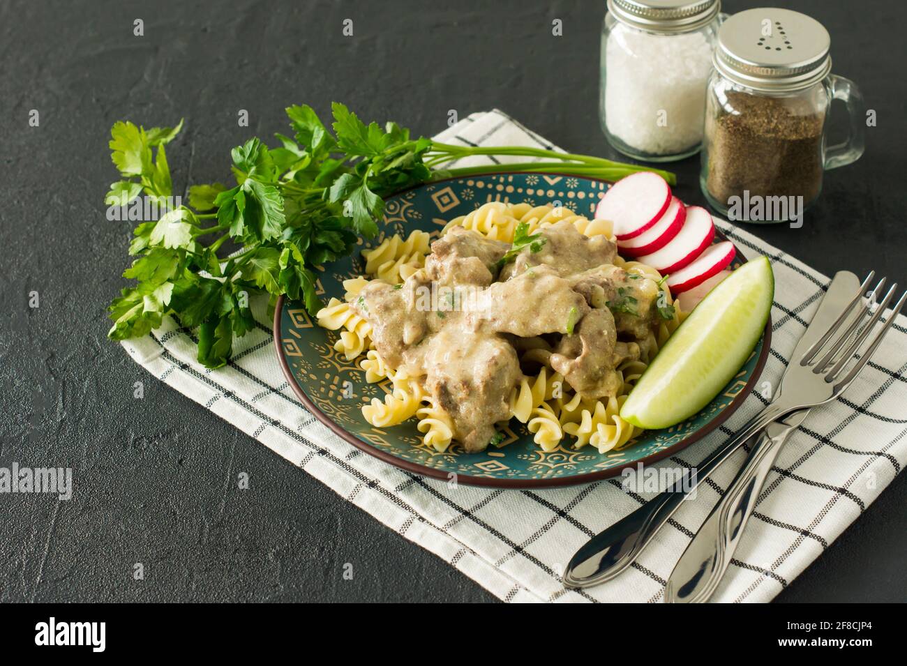 Pasta italiana a grani interi con fegato di pollo arrosto e cipolle servite su un piatto su sfondo marmoreo. Foto Stock