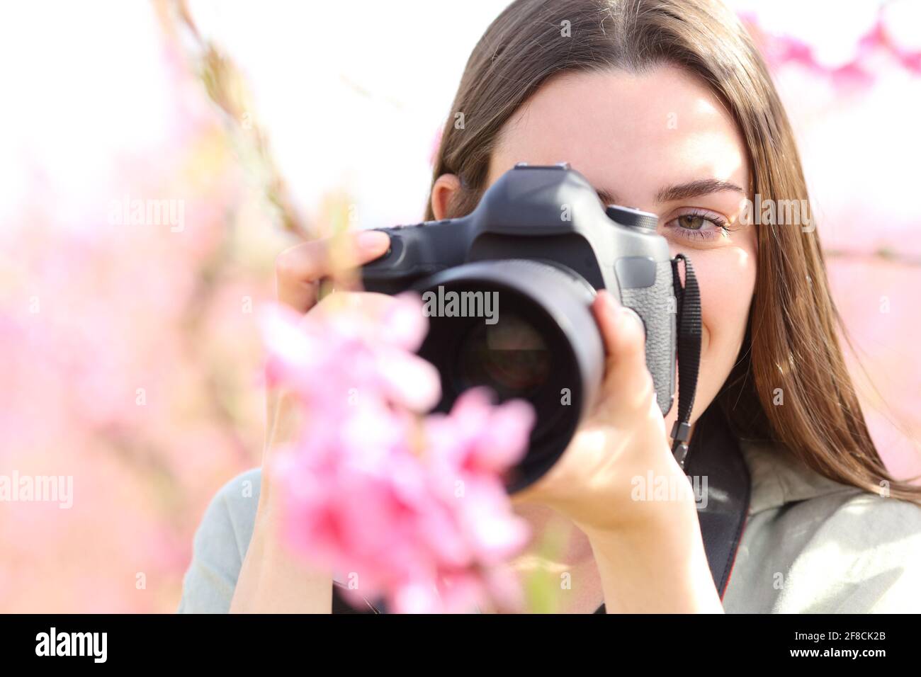 Vista frontale ritratto di un fotografo che fotografa fiori con macro obiettivo e fotocamera dslr in un campo Foto Stock