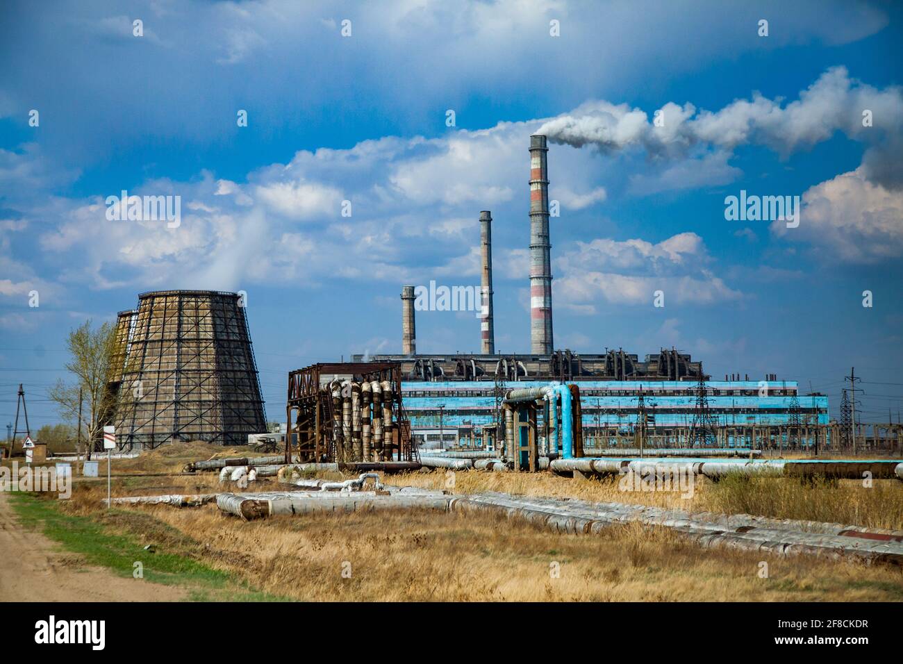 Centrale elettrica con torri di raffreddamento e camini della centrale di smocking. Cielo blu, nuvole. Kazakistan, Steppogorsk. Foto Stock