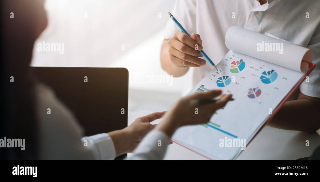 Primo piano gli uomini d'affari che discutono le tabelle e i grafici che mostrano i risultati del loro lavoro di squadra riuscito Foto Stock