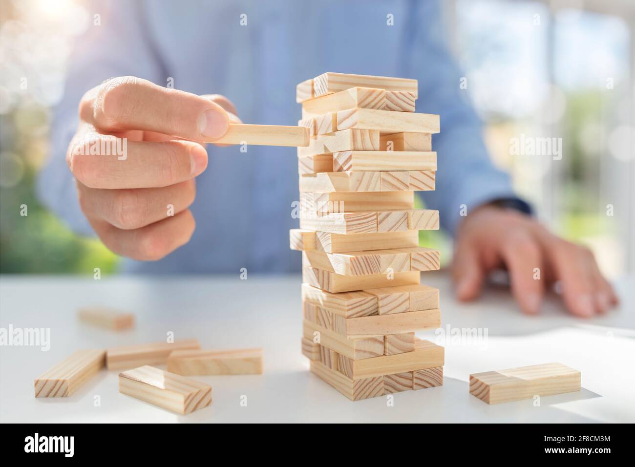 La pianificazione del rischio e della strategia nel business, imprenditore il gioco d'azzardo posizionando il blocco di legno su una torre Foto Stock