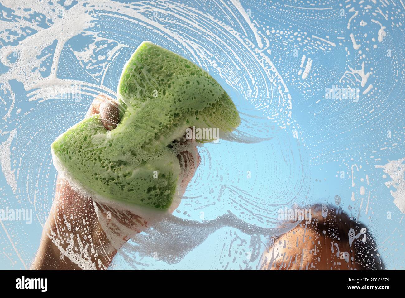 Detergente per cristalli con una spugna per lavare un finestrino con cielo blu chiaro Foto Stock